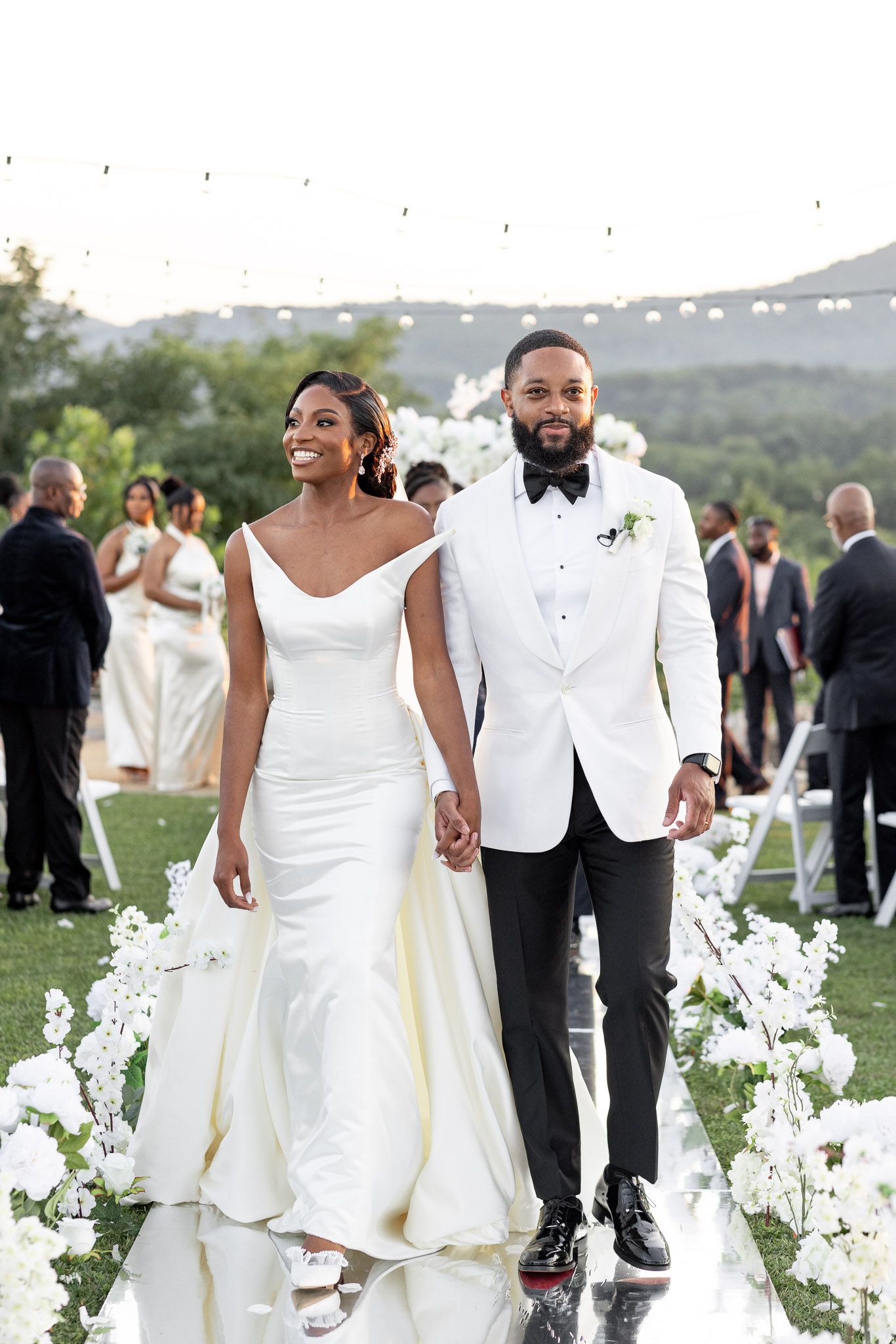 Wedding guests gather on a hillside lawn during an elegant outdoor ceremony with mountain views.