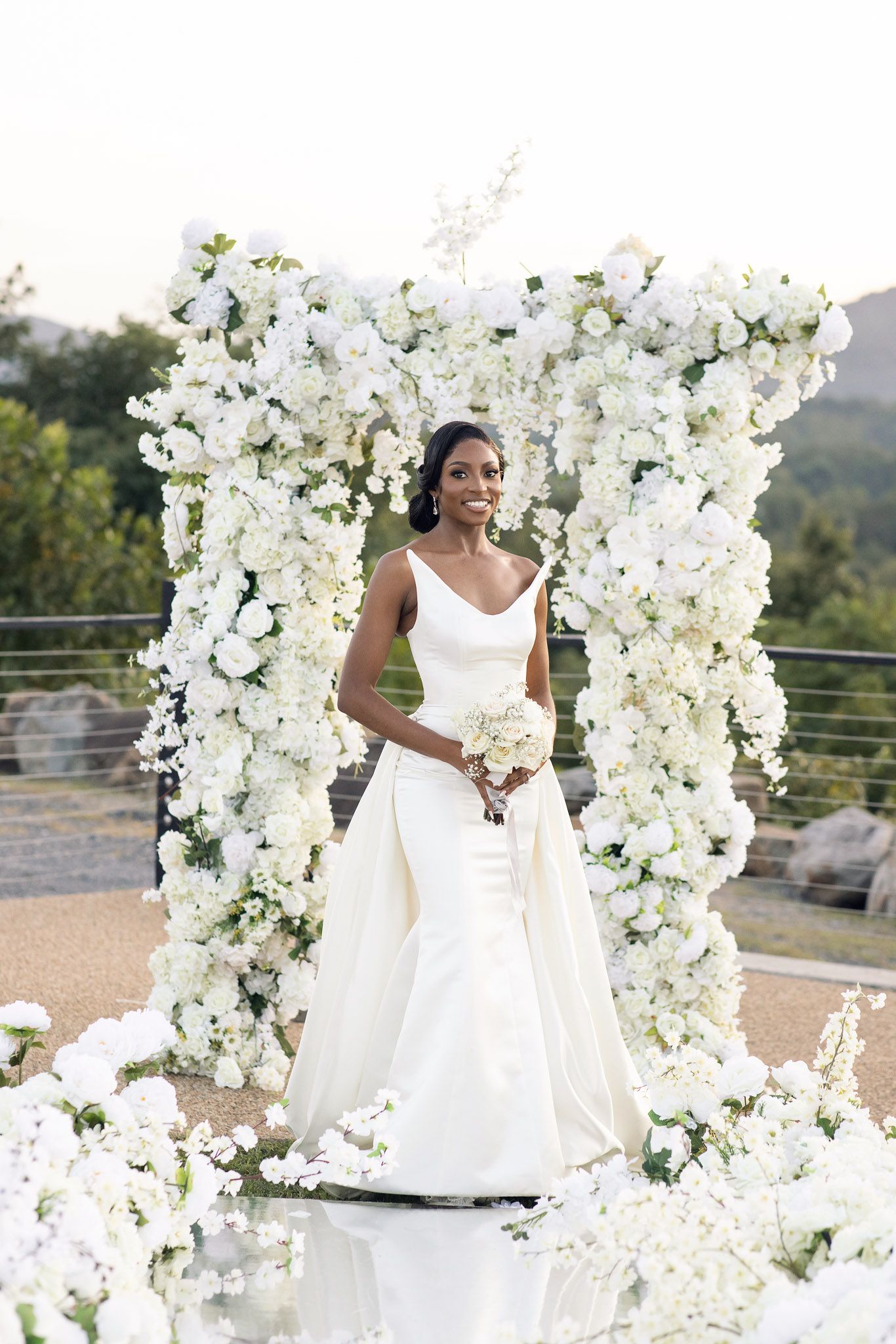 Stunning white orchid and rose wedding arch installation at an outdoor venue.