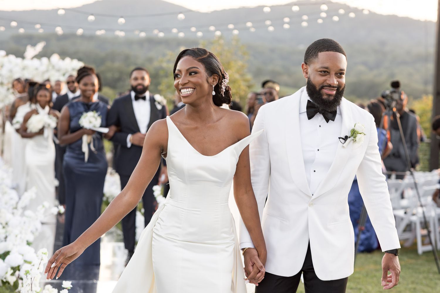 Elegant outdoor wedding celebration with white decor and scenic mountain views.