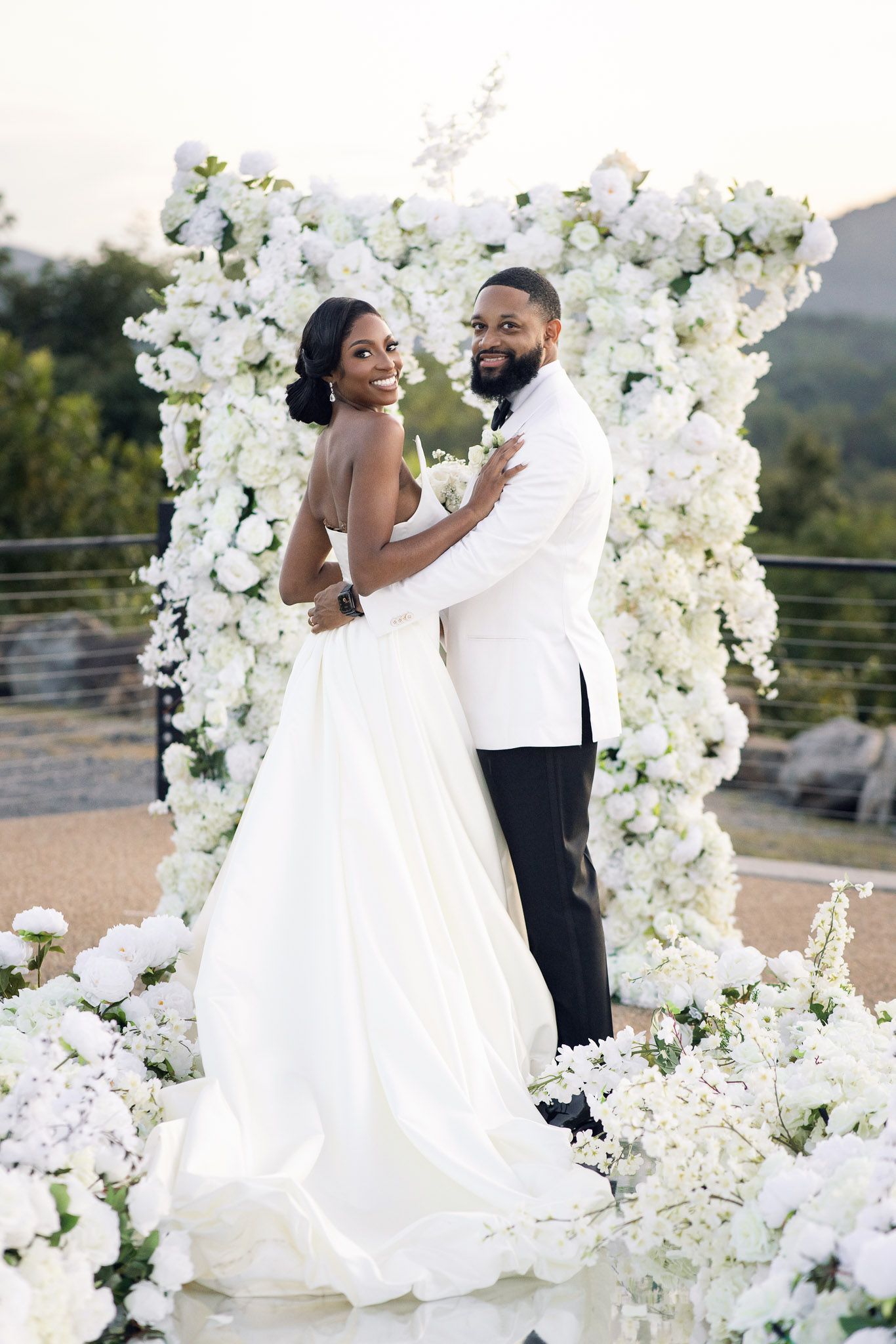 Beautiful wedding portrait with couple surrounded by white floral arrangements.