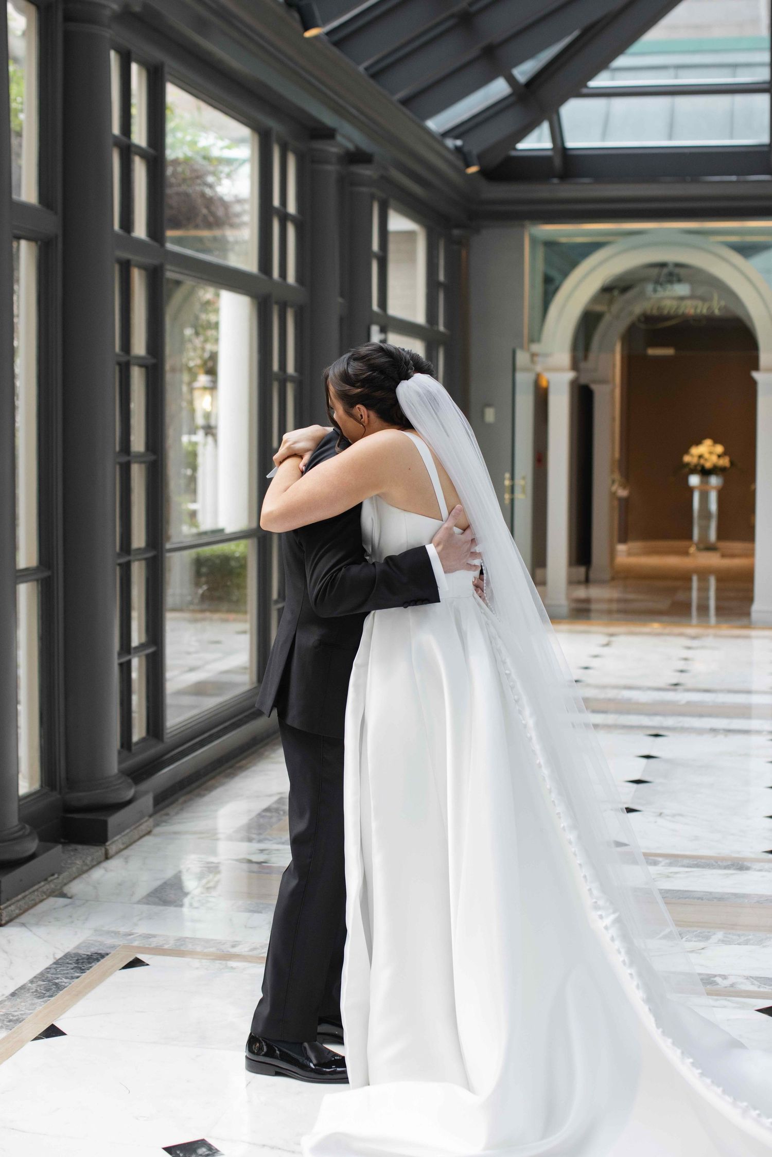 A romantic wedding sequence shows a couple embracing in an elegant hallway with large windows and architectural details.