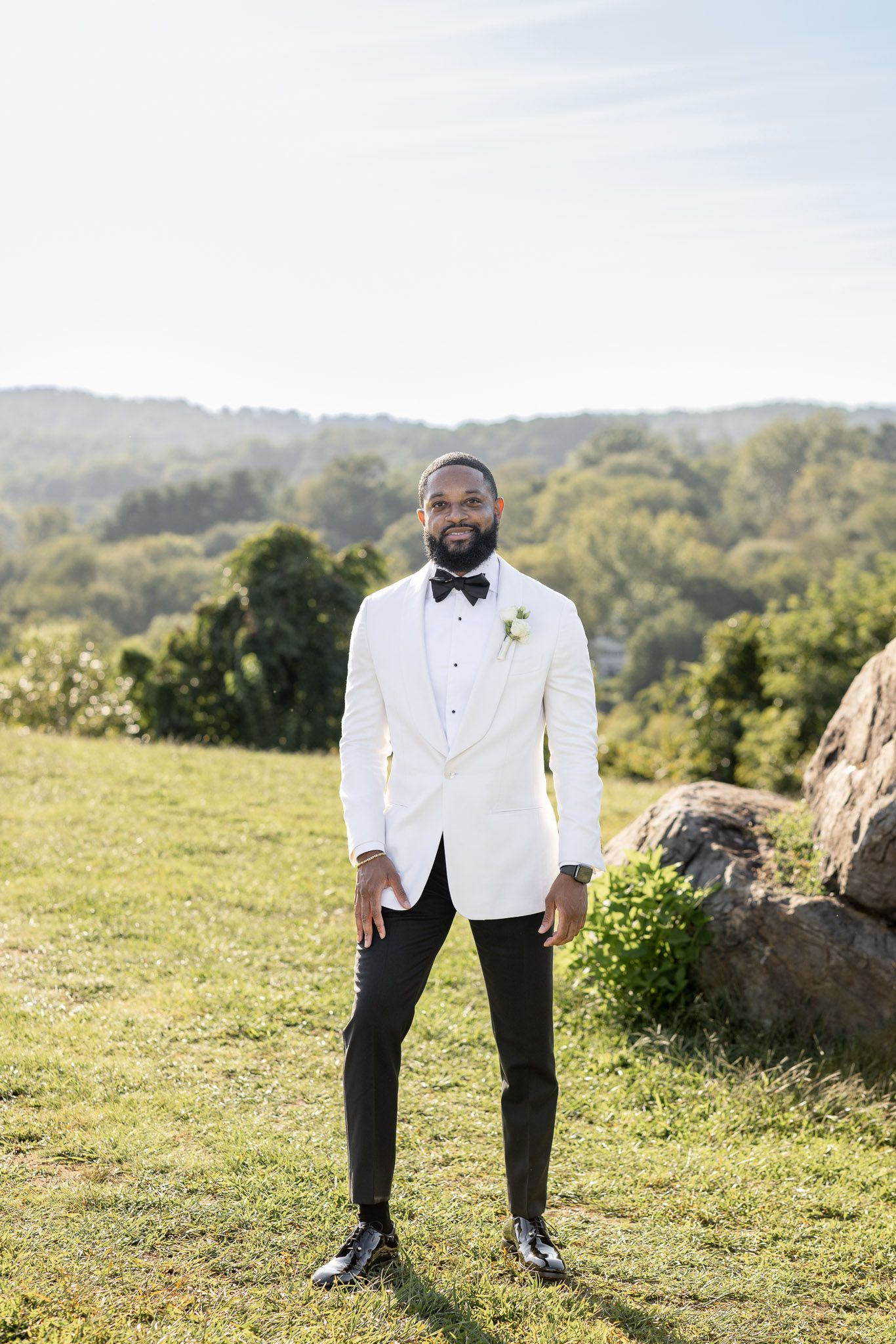 Wedding photography on scenic hillside with natural rock formations and green landscape.