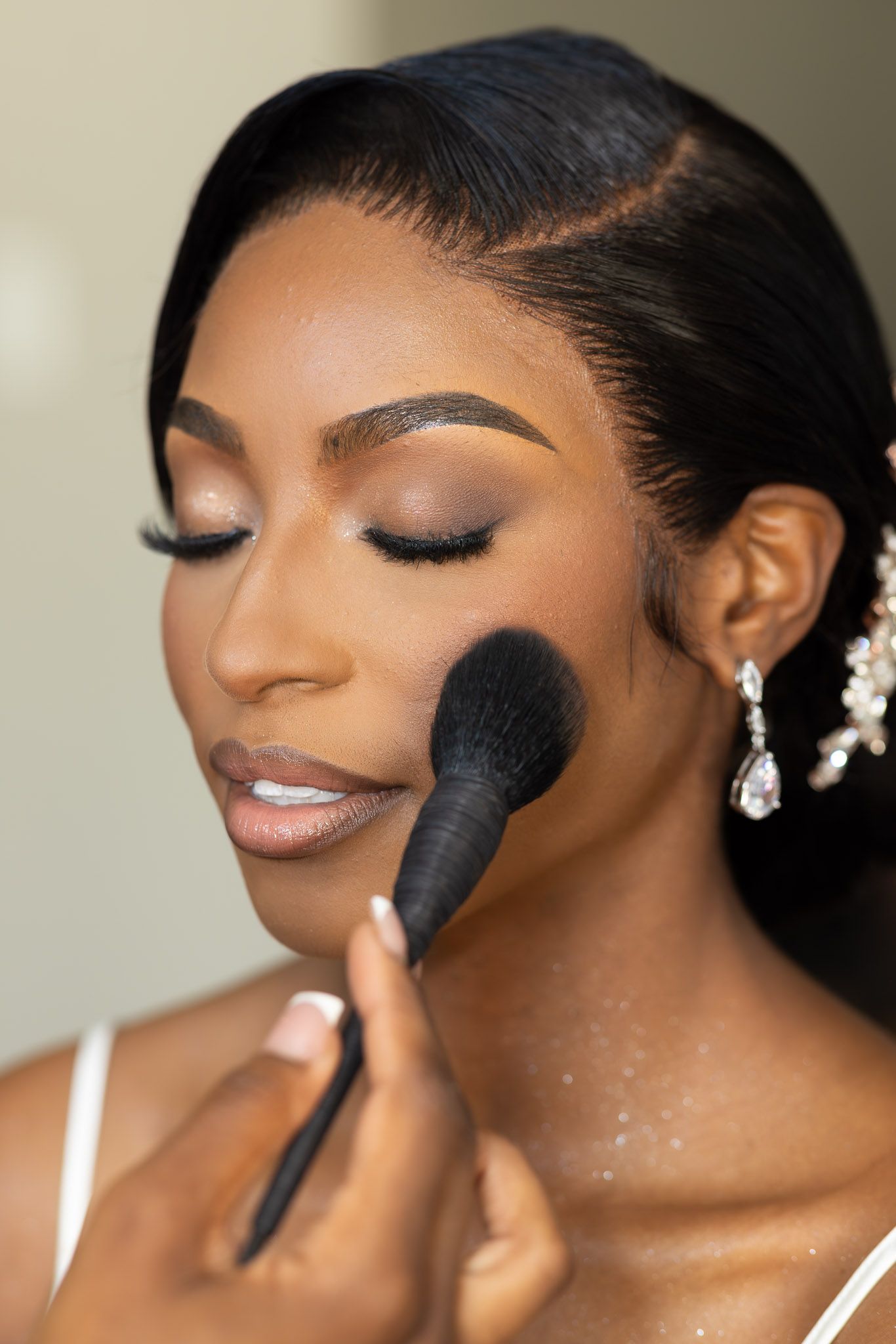 Close-up of makeup application showing precise contouring technique with a dark brush.