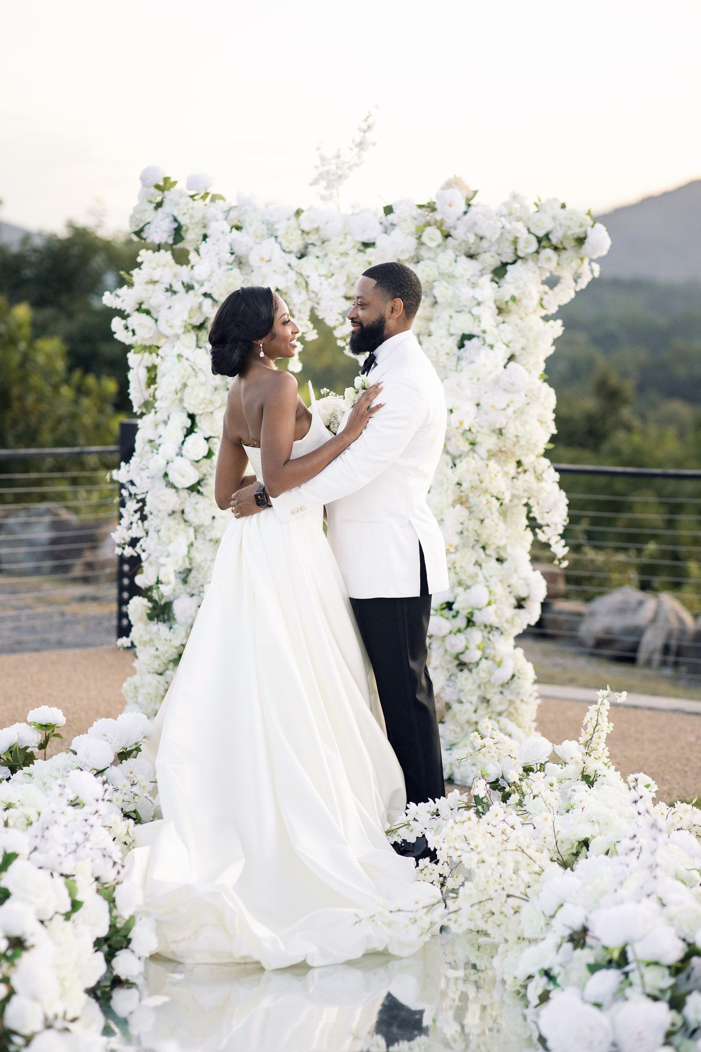 Intimate wedding moment captured against backdrop of white flowers and mountain views.