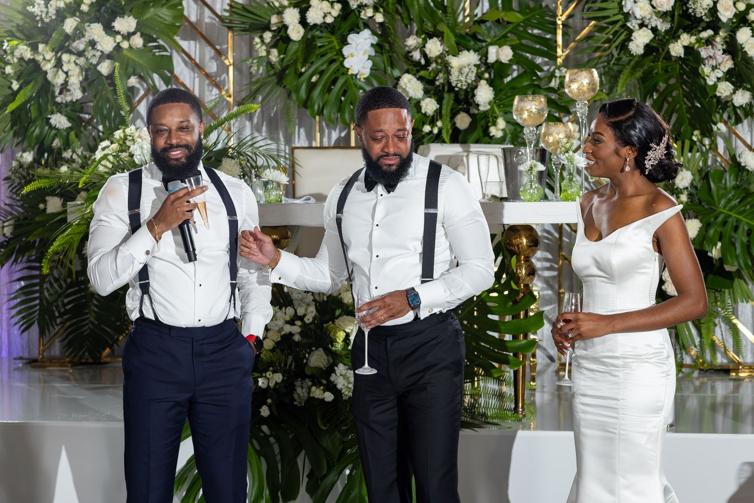 Wedding party in navy and white attire poses in front of elegant floral arrangements.