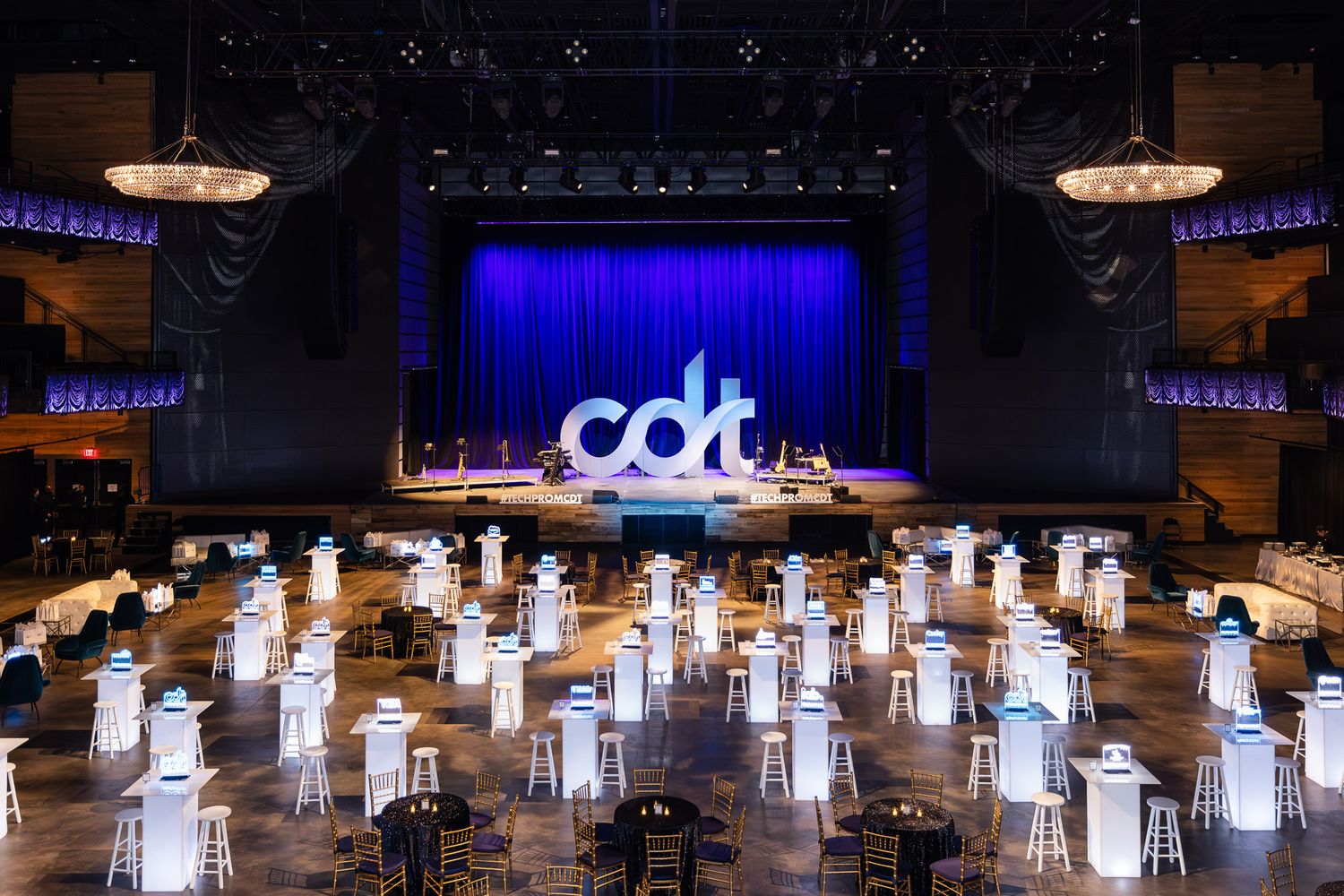 Illuminated white paper lanterns arranged in rows create a glowing art installation inside a dark performance space.