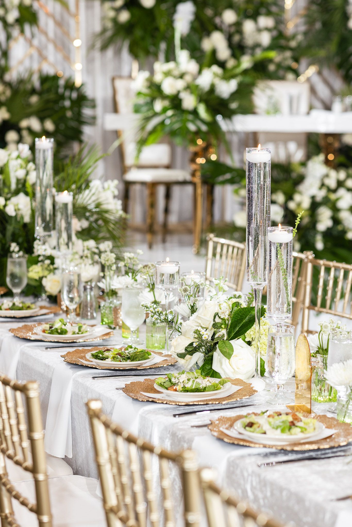 Elegant wedding table settings with gold chairs, white linens, and tropical floral centerpieces.