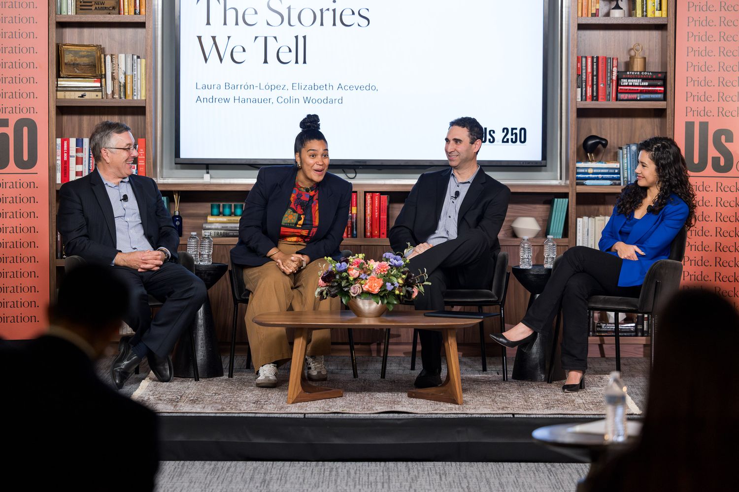 People seated in a bookstore or library setting during what appears to be a discussion panel or literary event.