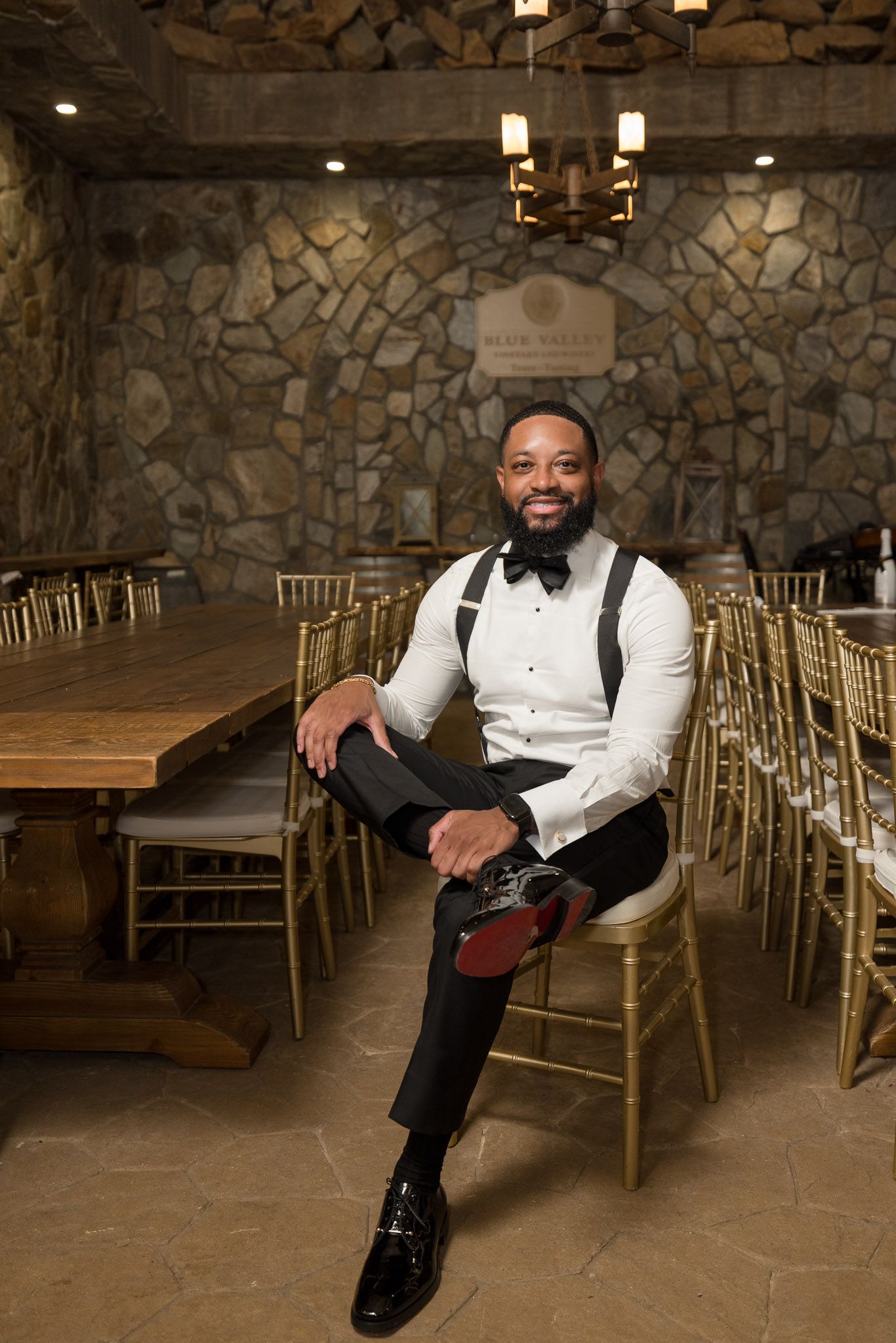 Formal wear against stone walls with gold chiavari chairs in an event space.
