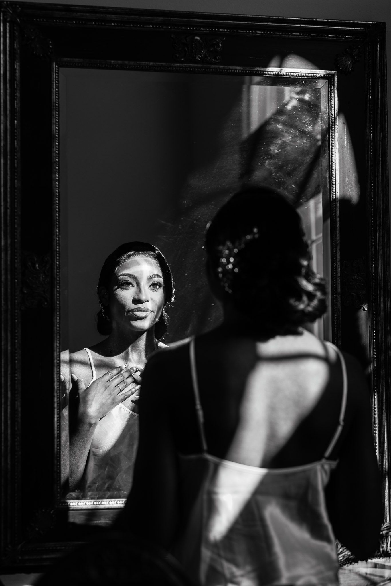 Artistic black and white reflection of bridal preparation in multiple mirrors.