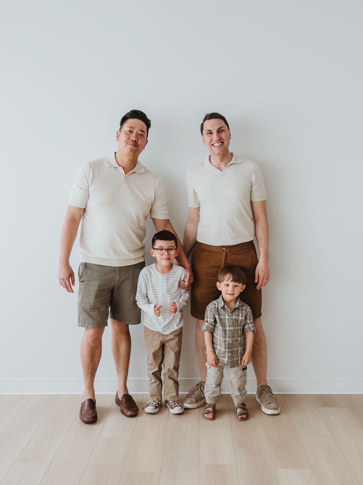 Two fathers with their young sons sharing playful moments during an extended family photography session in Spruce Grove.