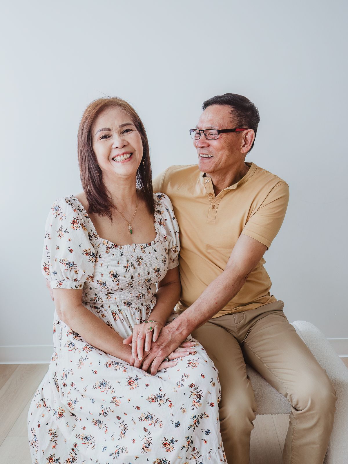 Grandparents laughing together during a multi-generational family photography session in a bright studio.