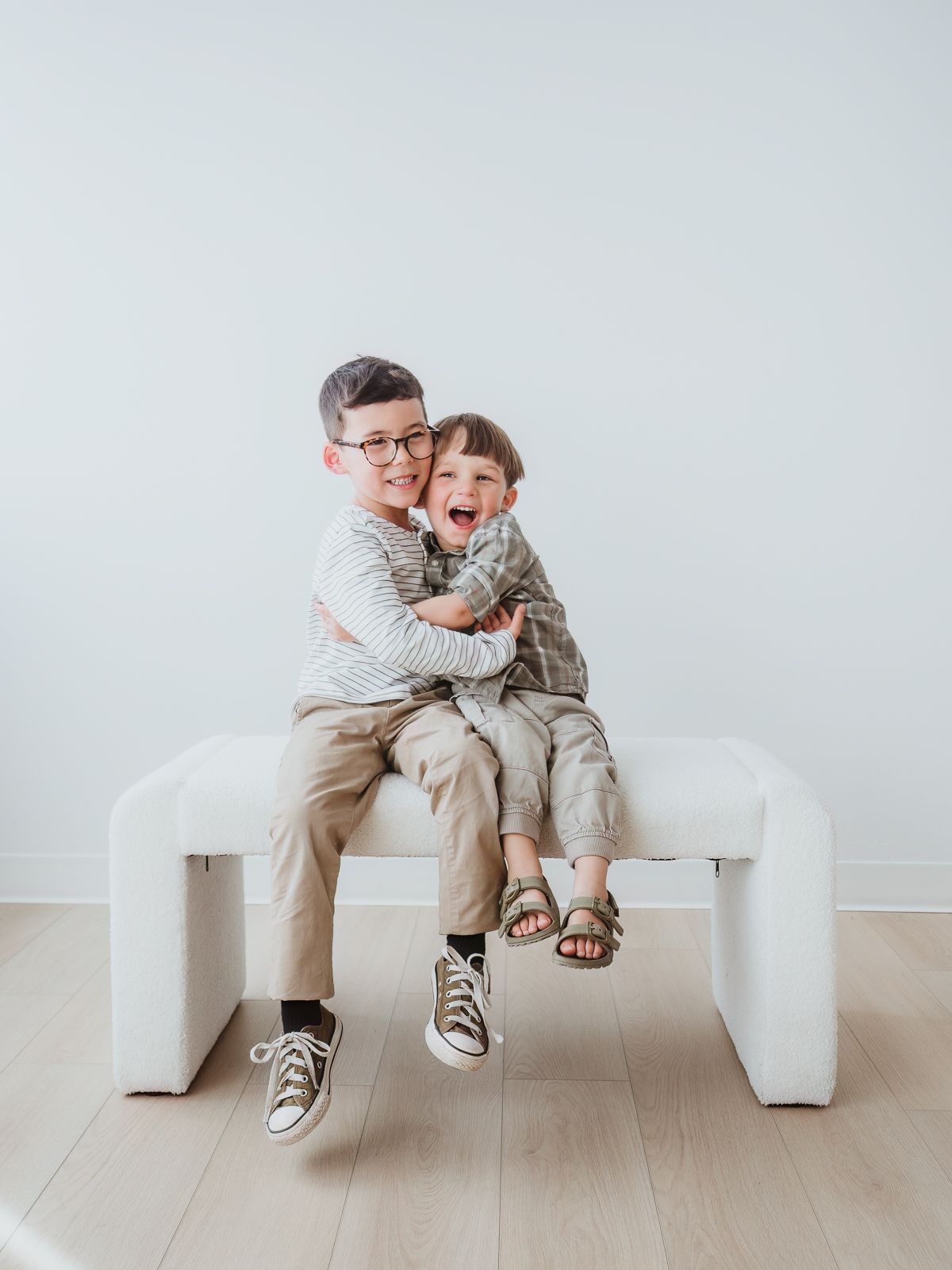 Young siblings sitting together and smiling during a family photography session in Spruce Grove.