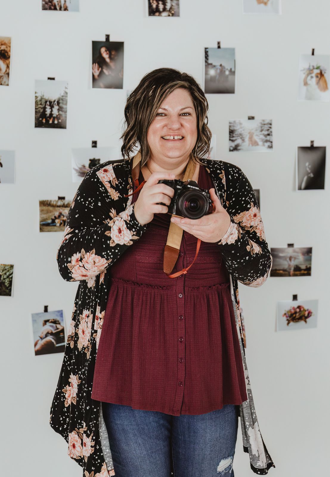 Edmonton area photographer Coral Konanz smiling with camera in studio surrounded by client artwork