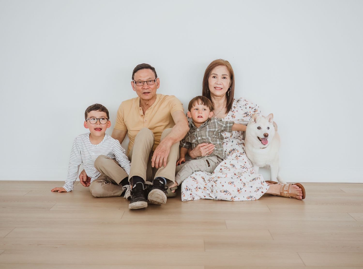 Grandparents laughing together during a multi-generational family photography session in a bright studio.
