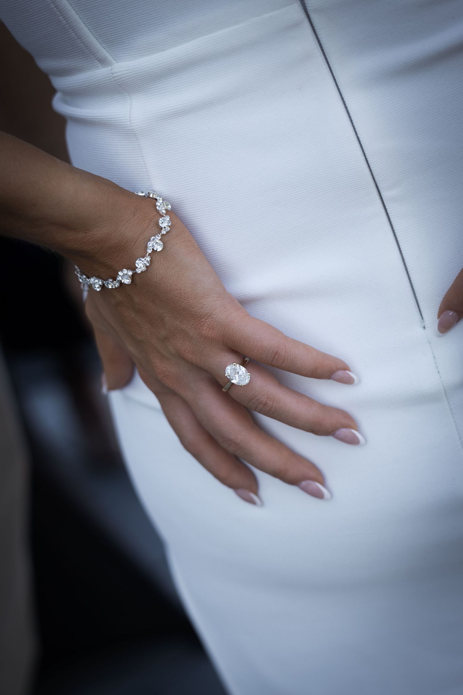 Close-up of bride's hand showing a stunning diamond engagement ring and floral diamond bracelet.