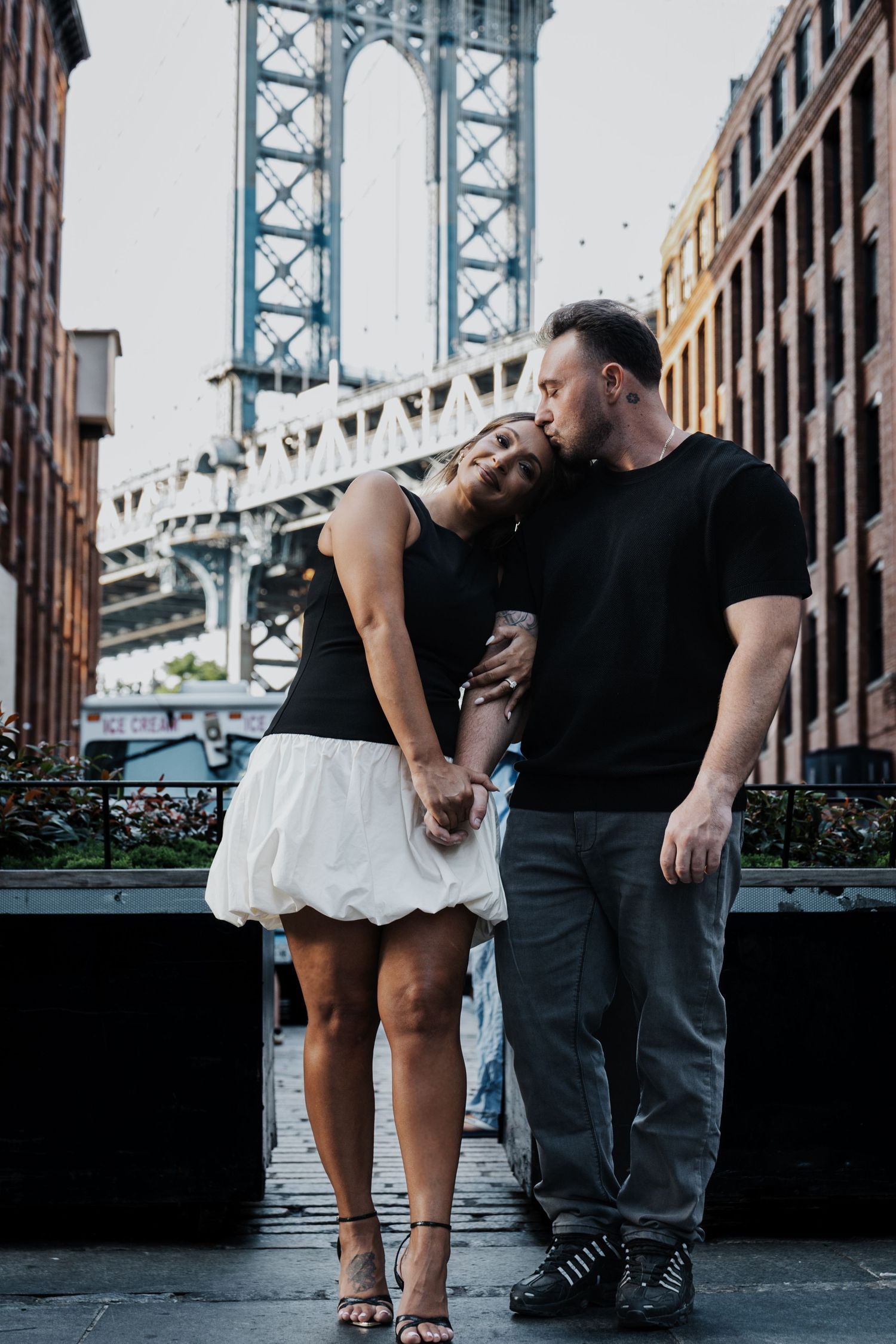 Interracial couple sharing a kiss near Manhattan Bridge in Brooklyn, New York.