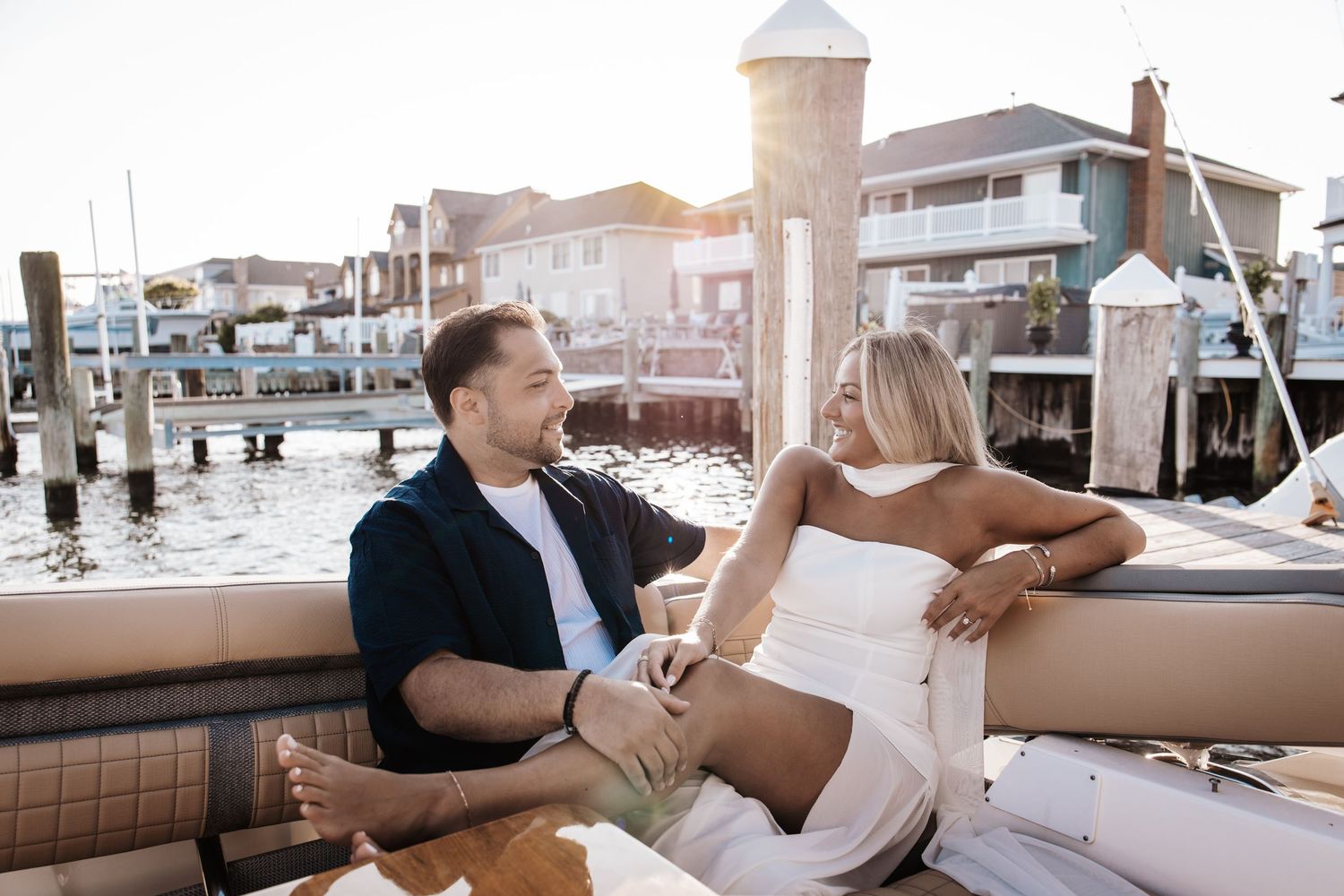 Couple relaxing on a luxury boat at a marina during golden hour engagement session in New Jersey.