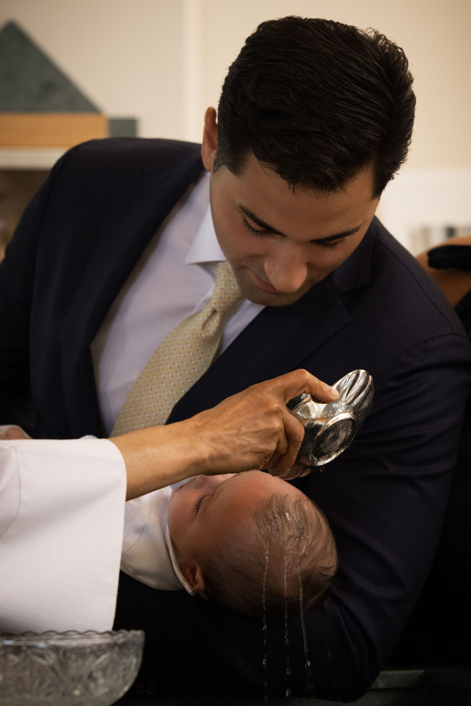 Baby being baptized with holy water poured over head during christening ceremony in Staten Island.