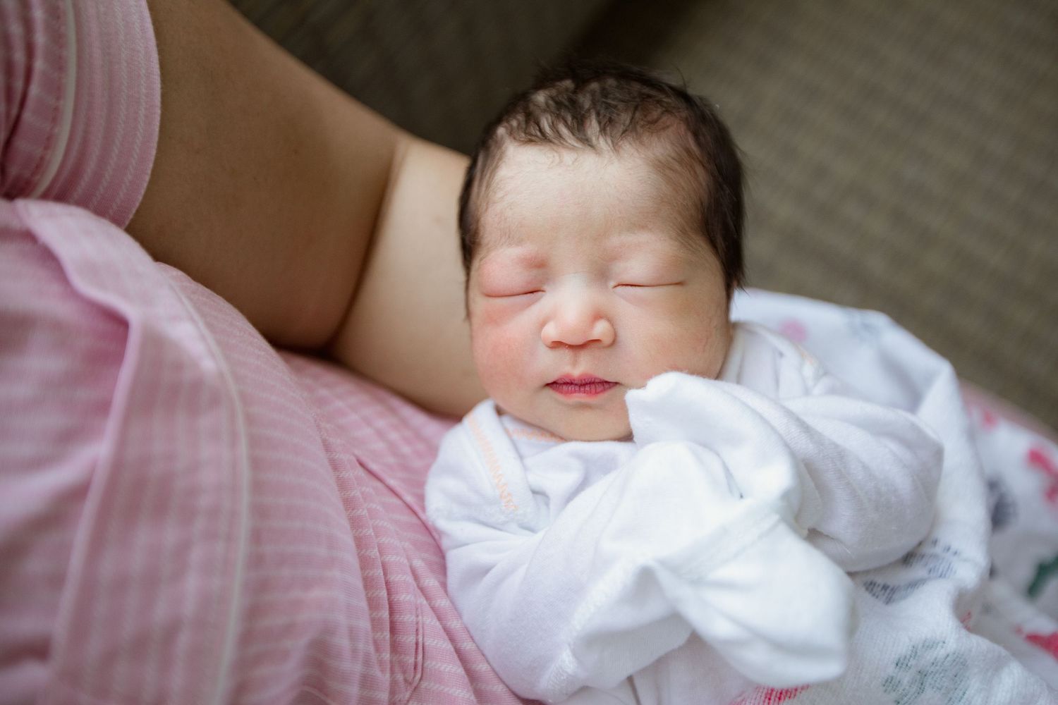 A peaceful newborn sleeping soundly in white clothing.