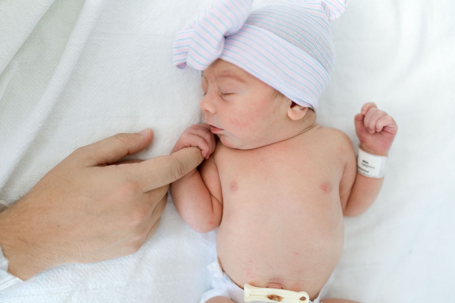 Dad holding newborn baby's finger during their Fresh 48 session with Bree Elle Photography in Beaumont, TX at St. Elizabeth hospital.