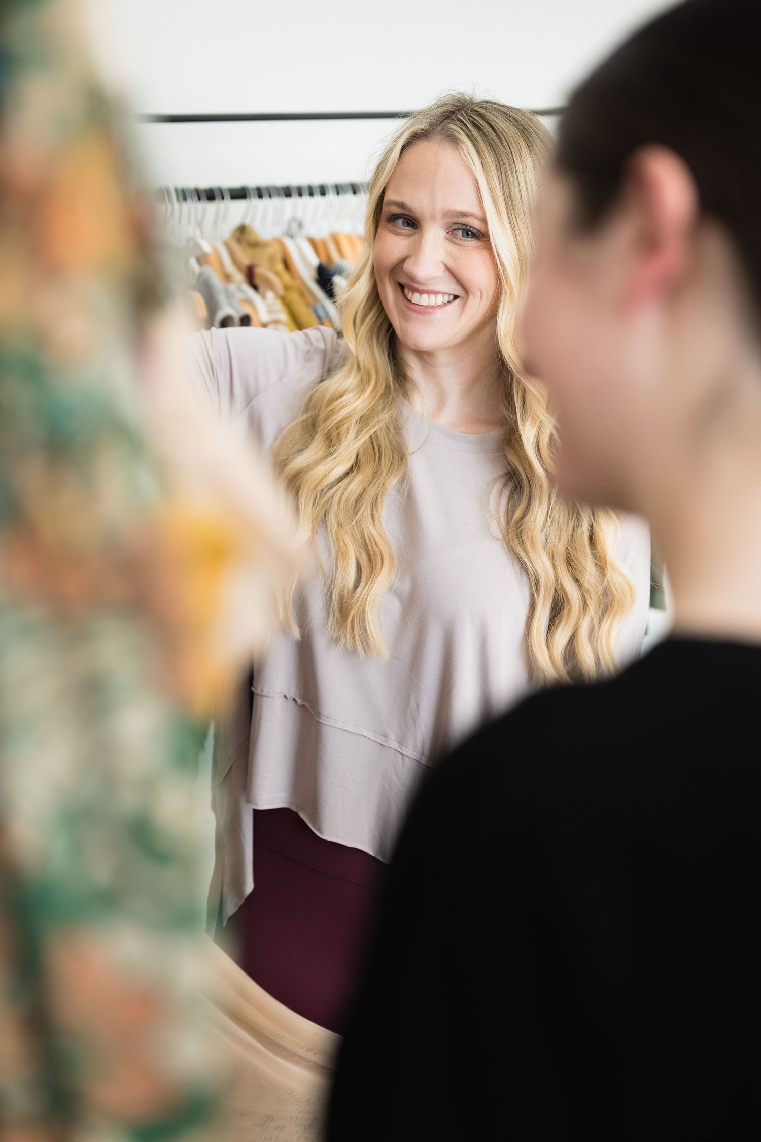 A customer browses clothing on racks in a boutique retail store.
