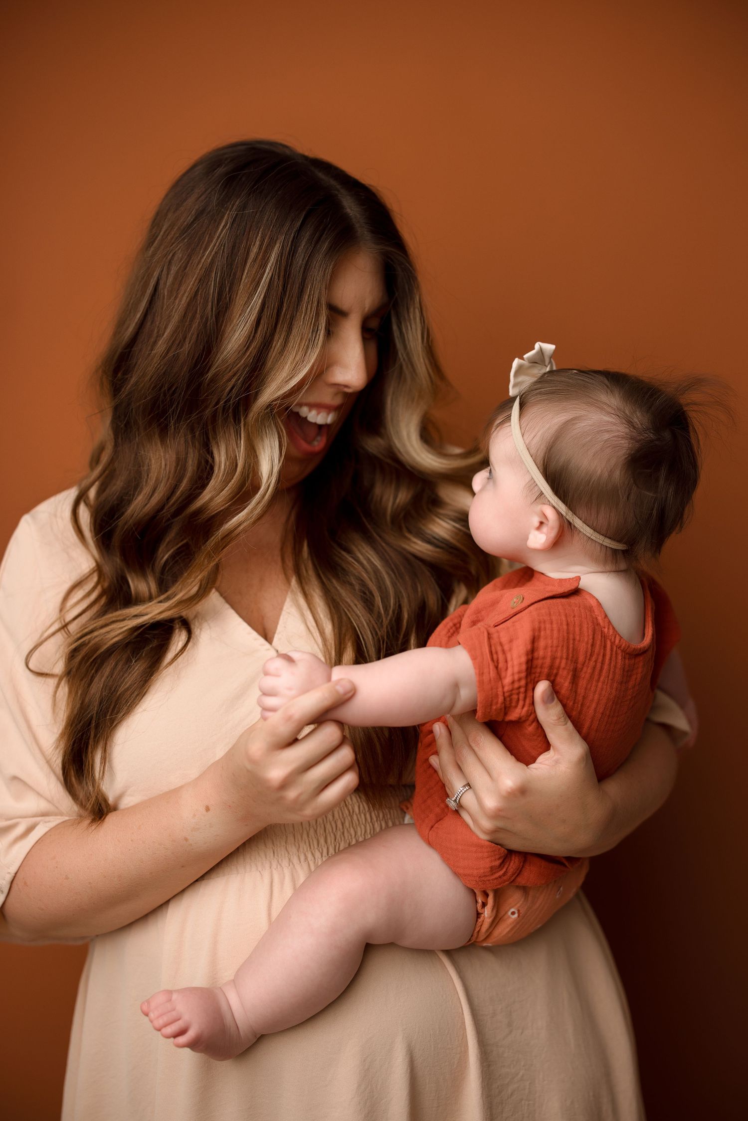 A series of tender moments between parent and baby in warm tones against a brown backdrop.