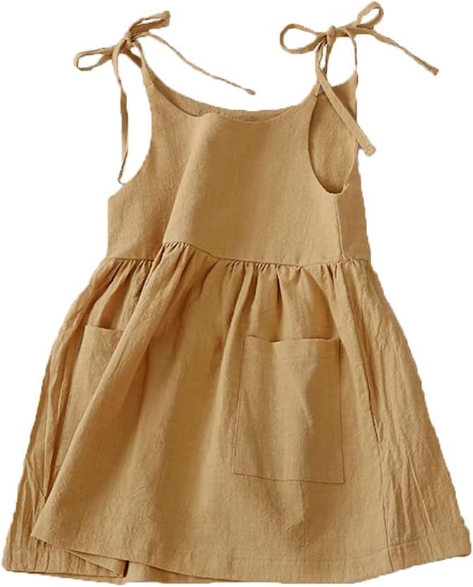 Row of four beige linen baby dresses or tops with tied shoulder straps and ruffled hems displayed on white background.