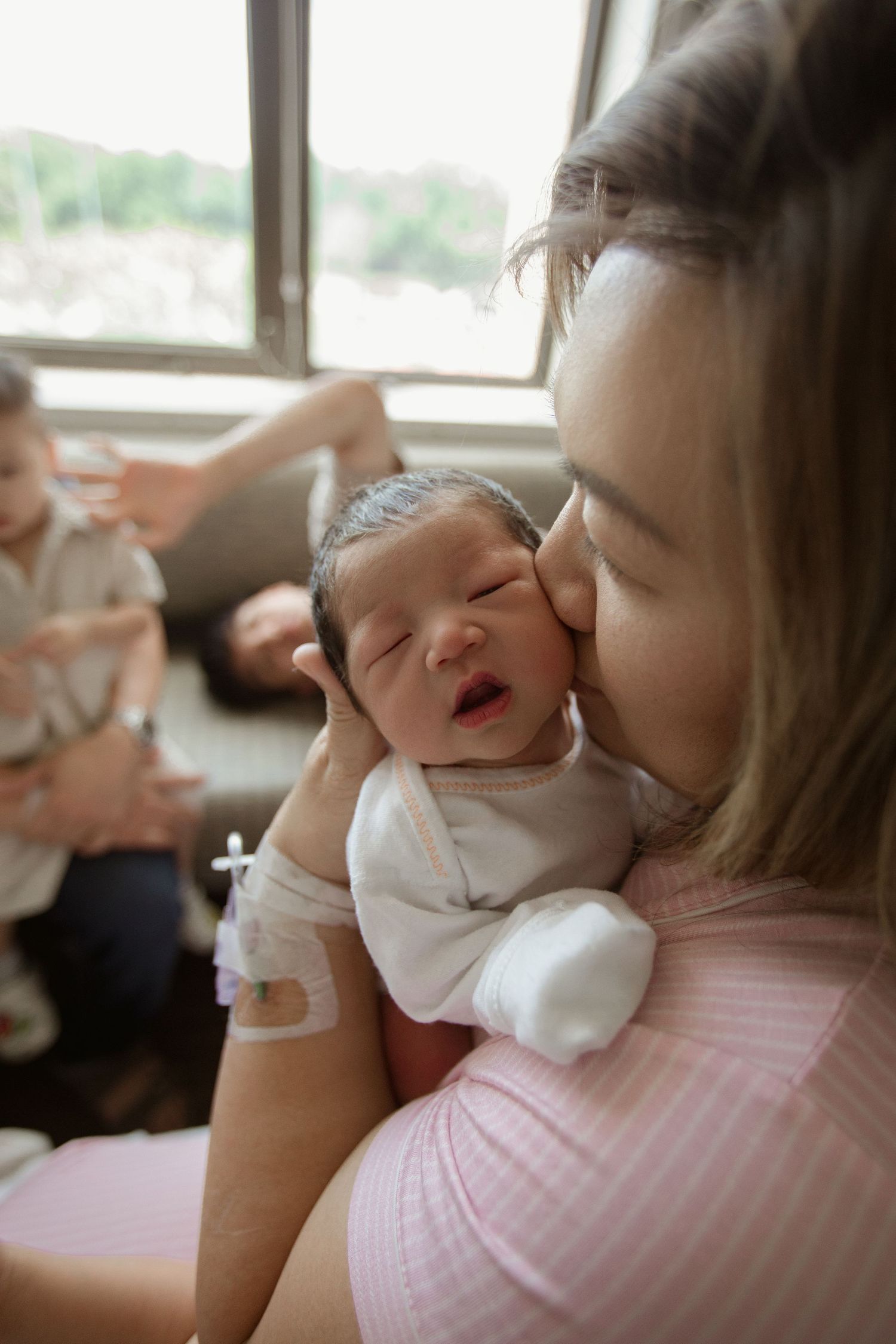 Tender moment between parent and newborn in sunlit room.