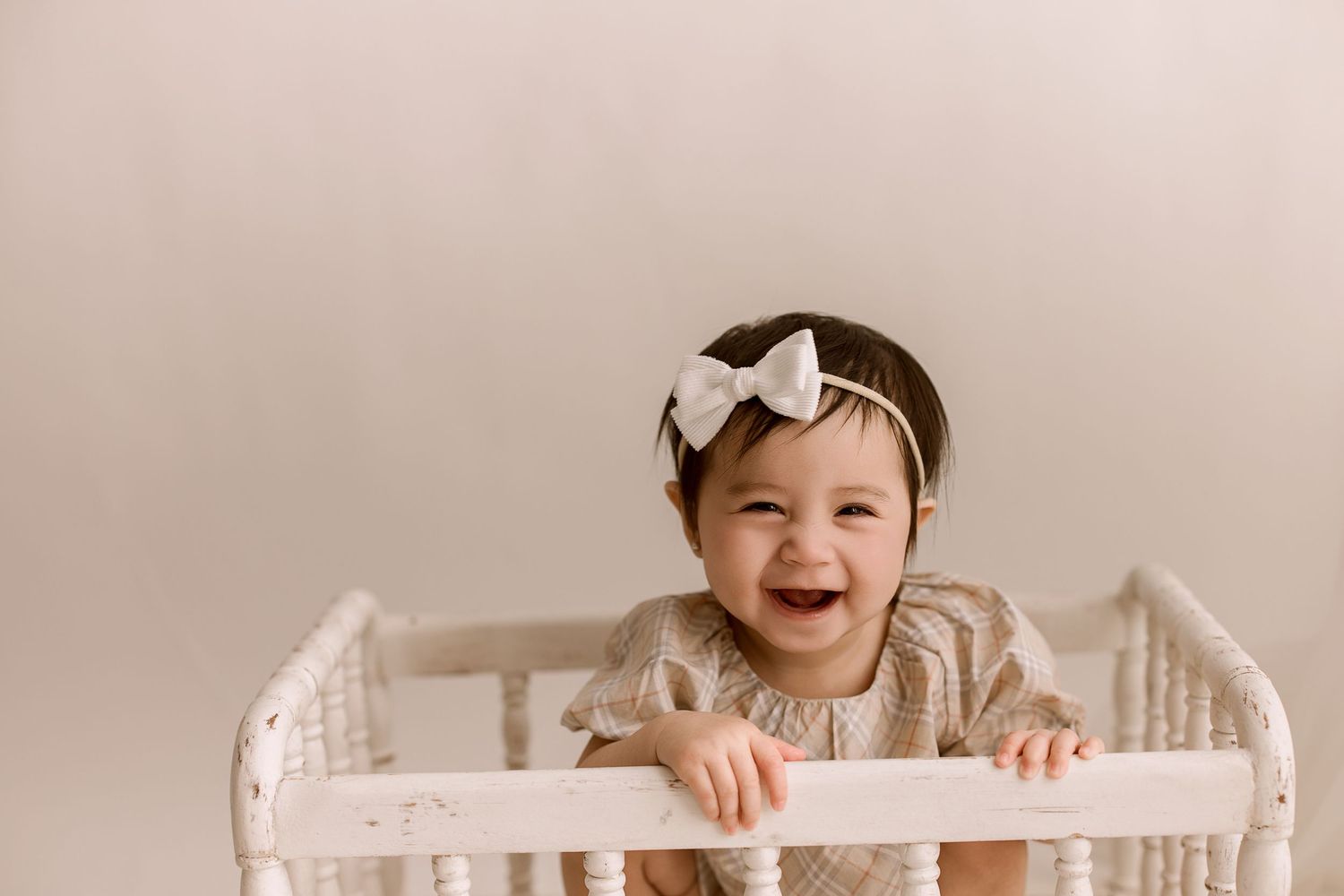 A series of milestone photos showing a baby growing from newborn to one year old in a white crib.