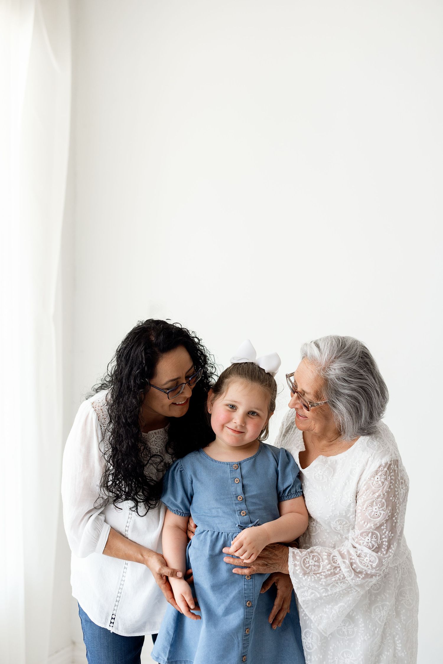 A series of candid family moments captured in soft white tones showing loving interactions between three generations.