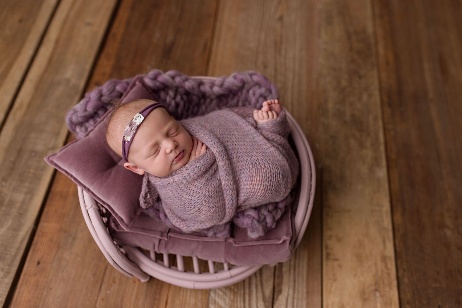 Six professional newborn photography portraits arranged in a row showing baby in pink and mauve tones on wooden surfaces.