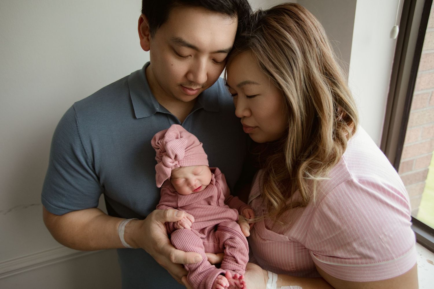 Intimate family moment with newborn wearing pink outfit.