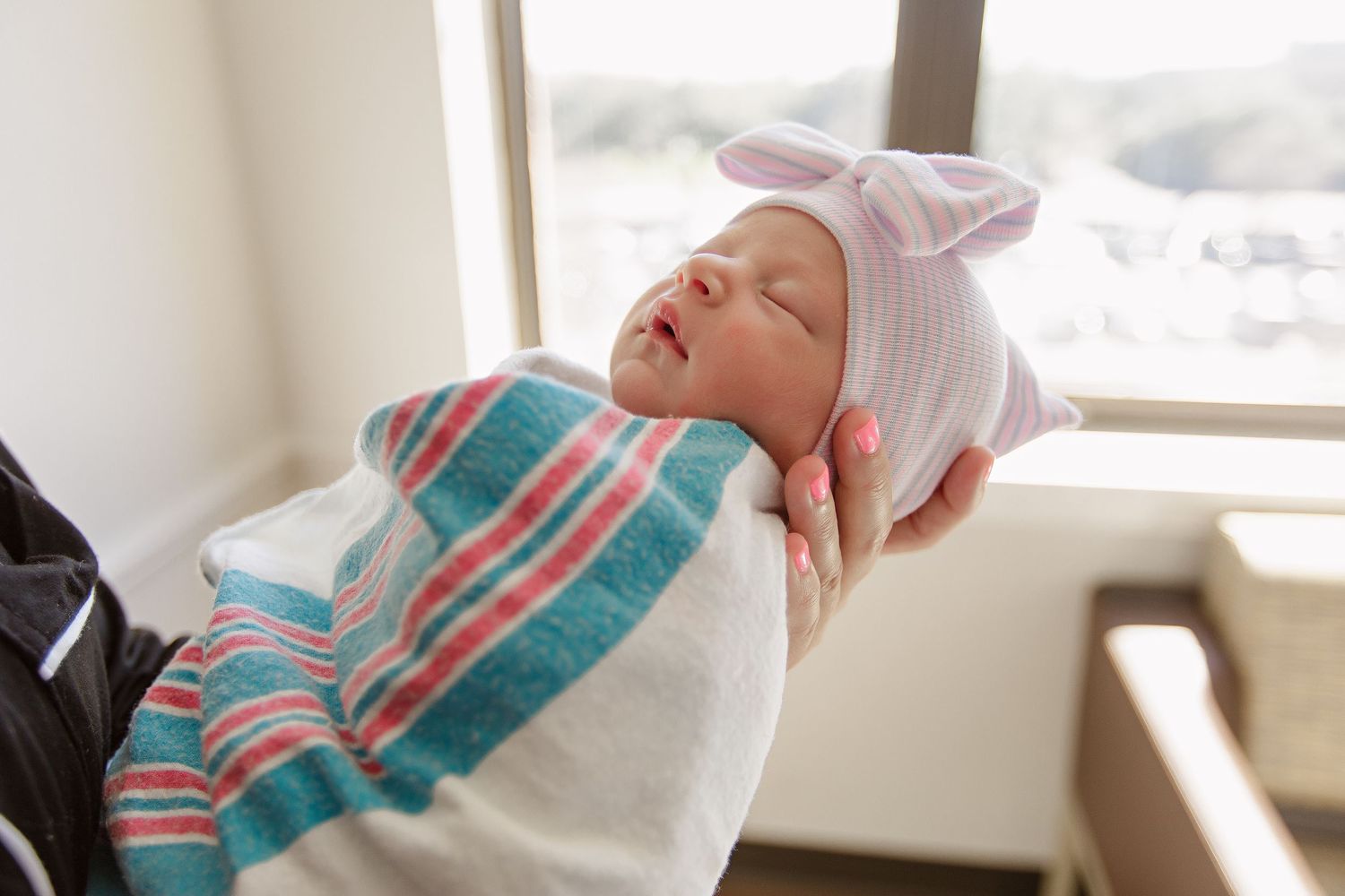 Newborn sleeping in hospital with blue and pink striped blanket during Fresh 48 session in Beaumont hospital.