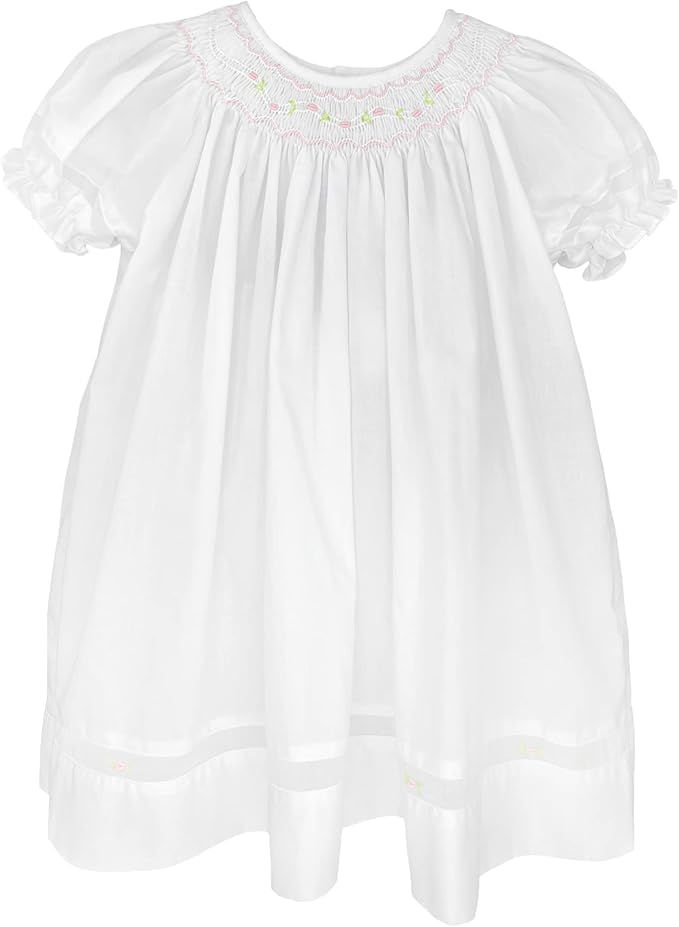 Three vintage white smocked baby dresses with puff sleeves and delicate floral embroidery displayed side by side.