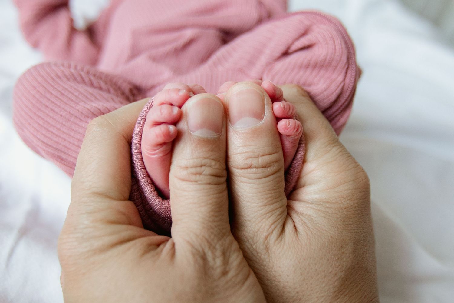 Close-up of tiny baby feet being held in adult hands.