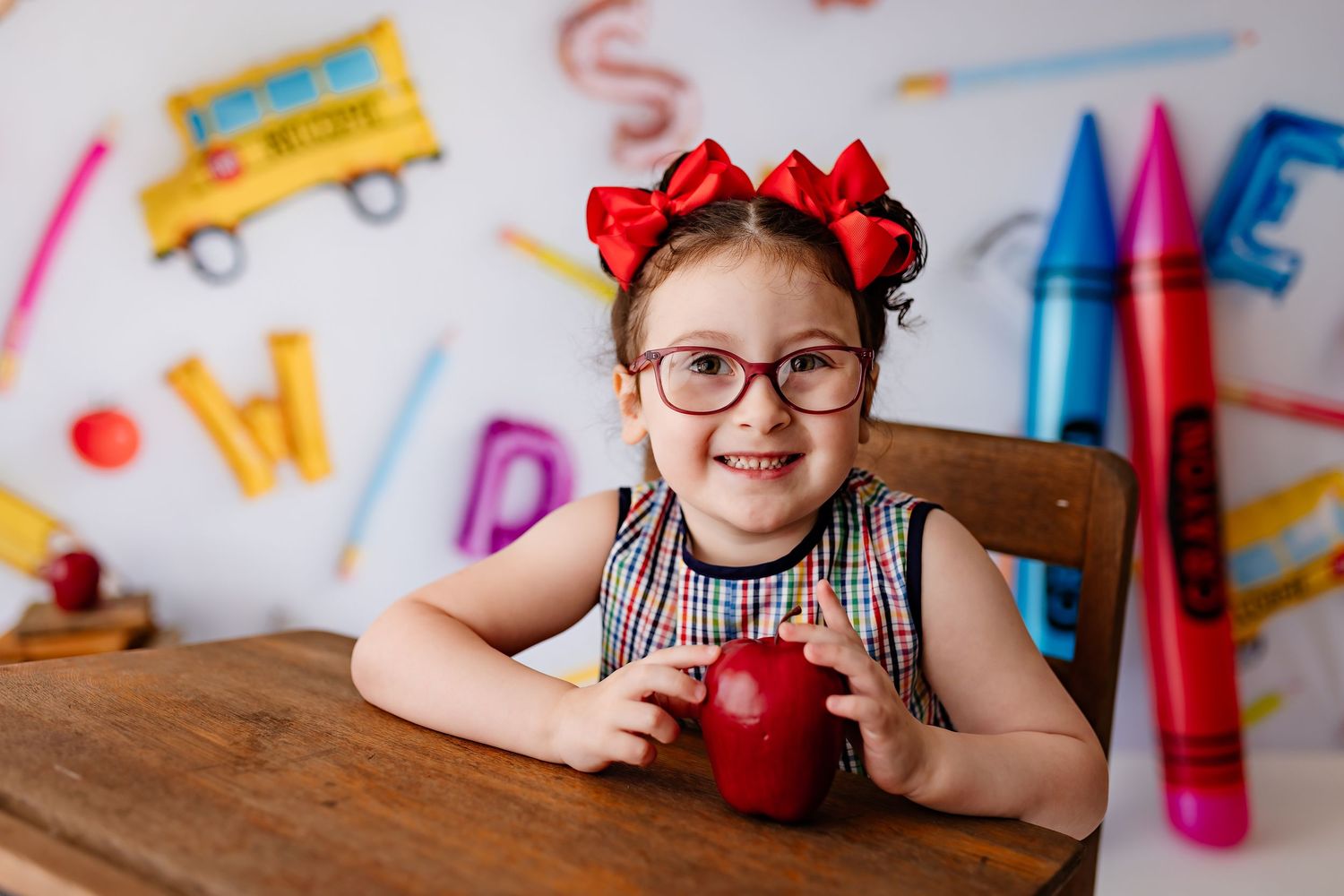 School-themed portrait with red bows against background of colorful pencils and educational symbols.
