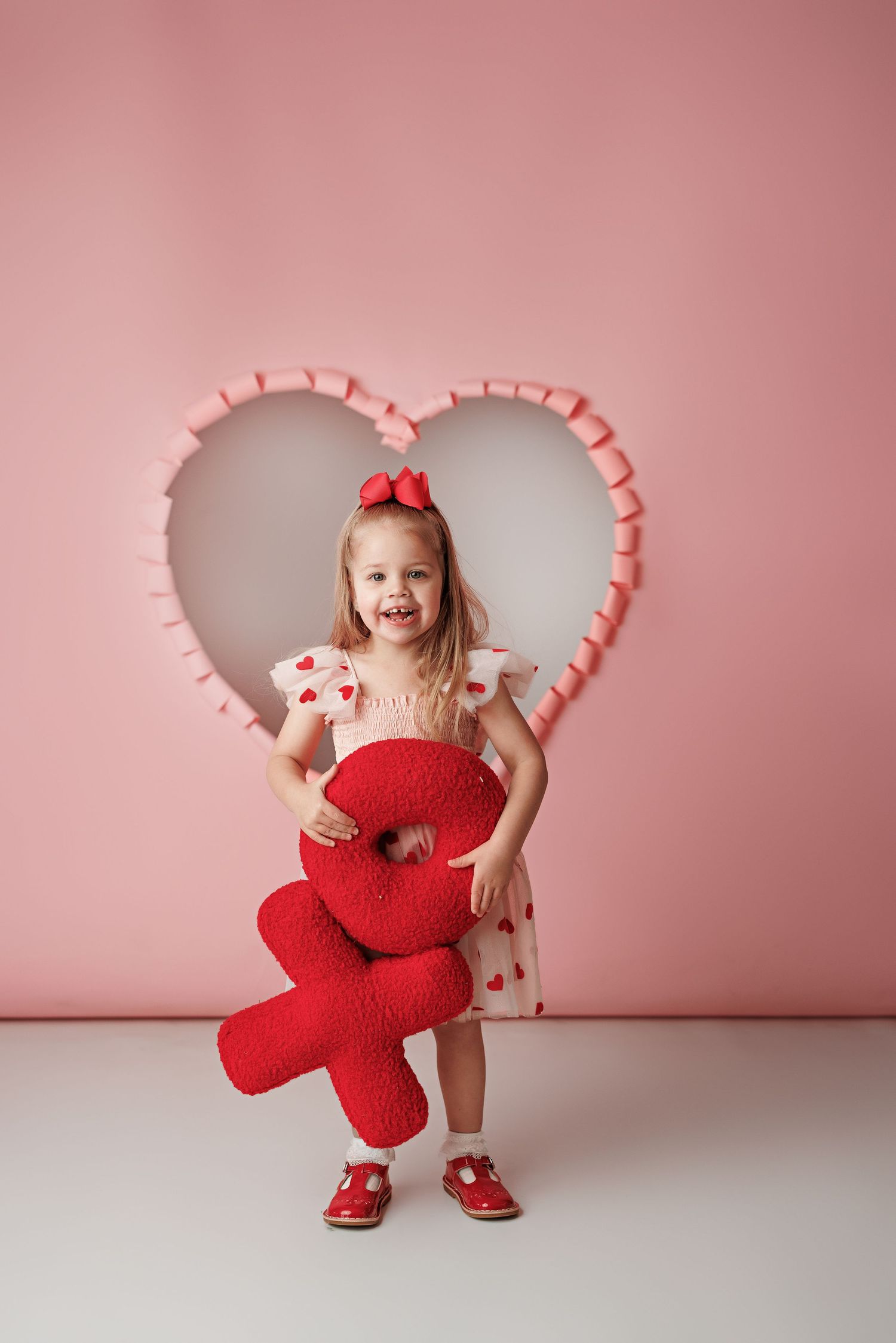 Valentine's portrait setup with pink heart frame and red teddy bear prop.