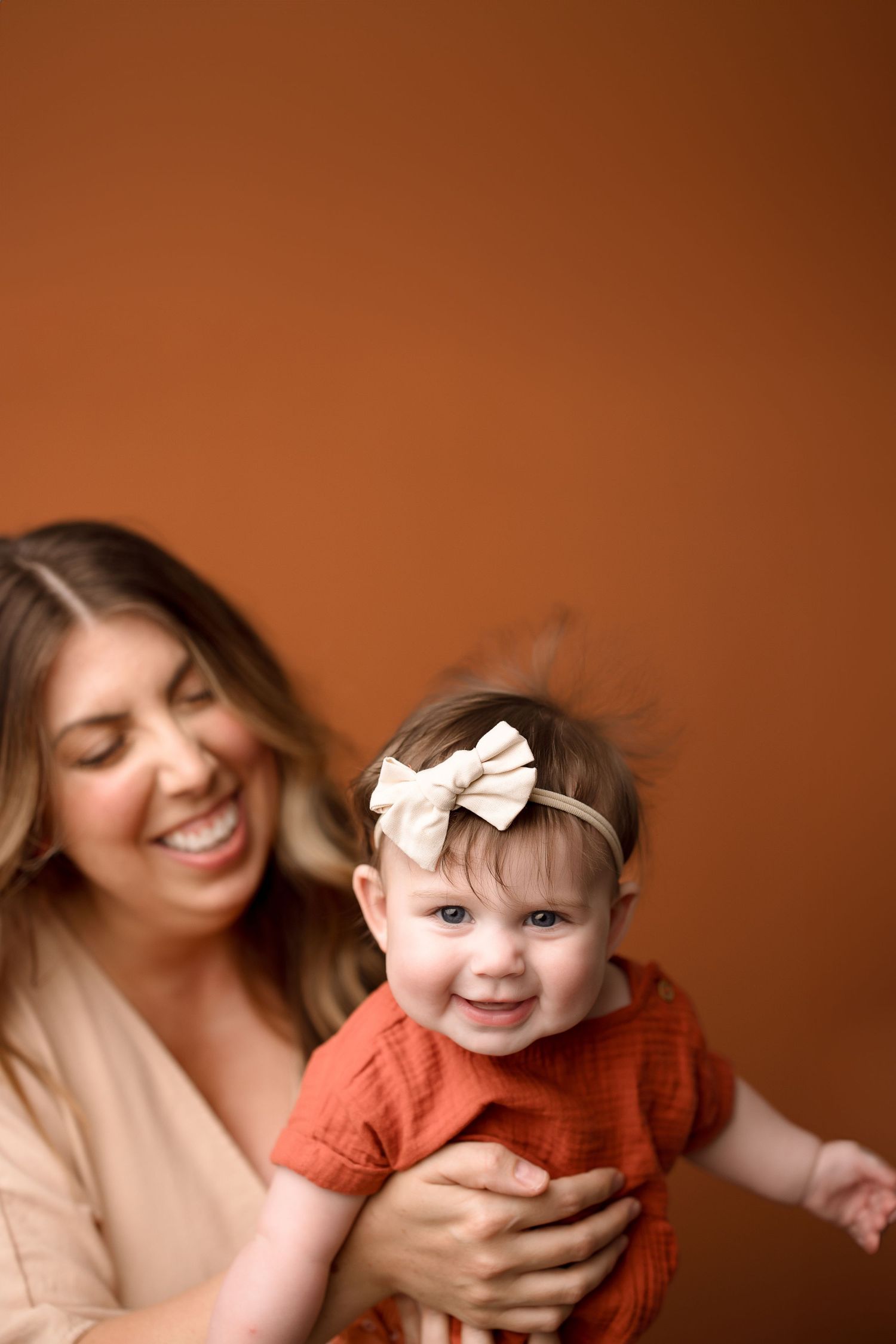 A series of candid photos showing joyful moments between a parent and baby in warm orange tones.