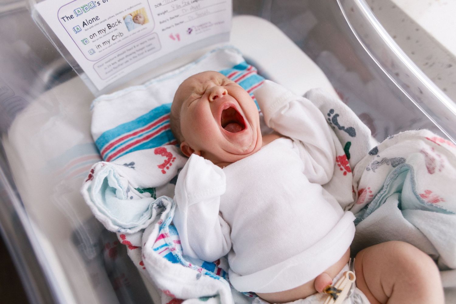 Photos showing newborn baby in hospital bassinet with striped blanket for Fresh 48 session.