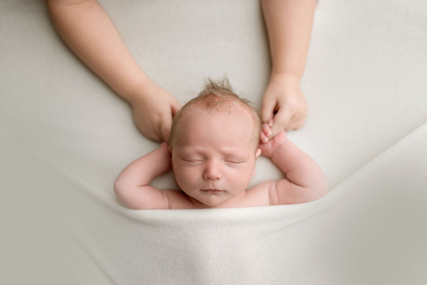 A series of minimalist newborn baby photos showing tiny feet and head details against a soft white background.