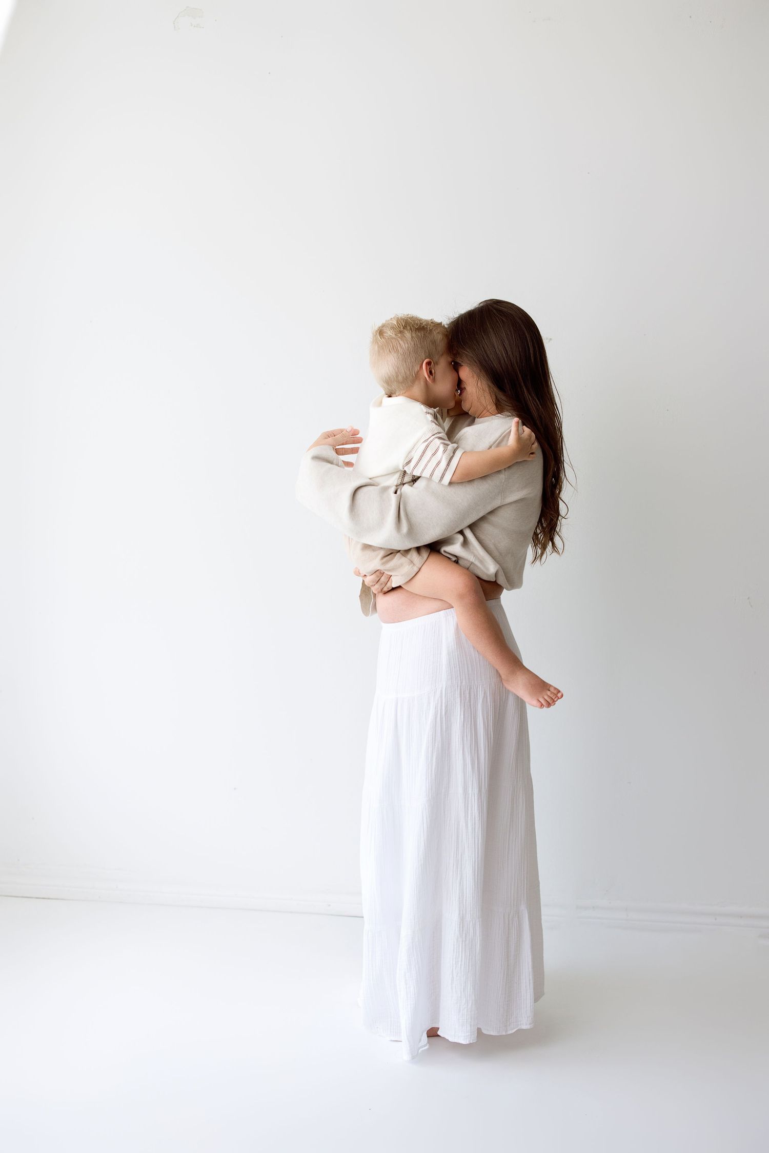 A series of minimalist photos showing tender embraces between two figures wearing white against a light background.