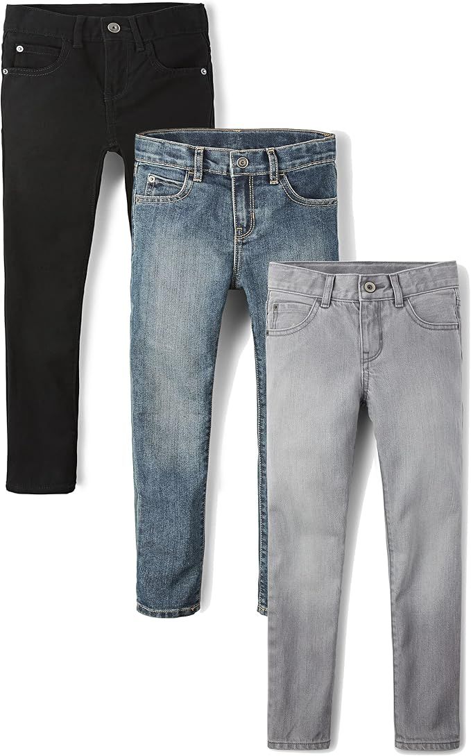 Collection of denim and gray jeans in different washes and styles laid out in a row against white background.