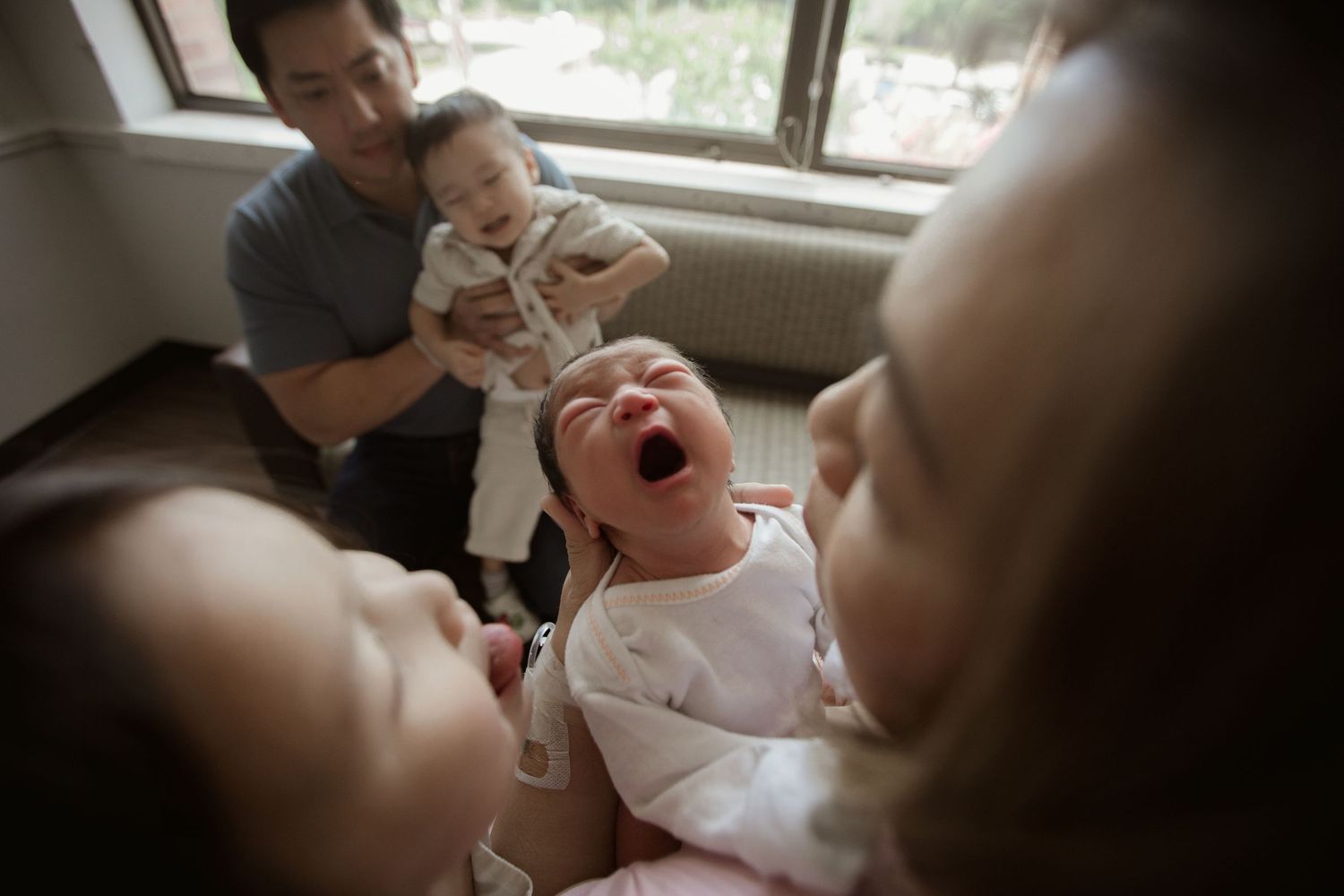 A laughing child in a hospital room while others gather around.