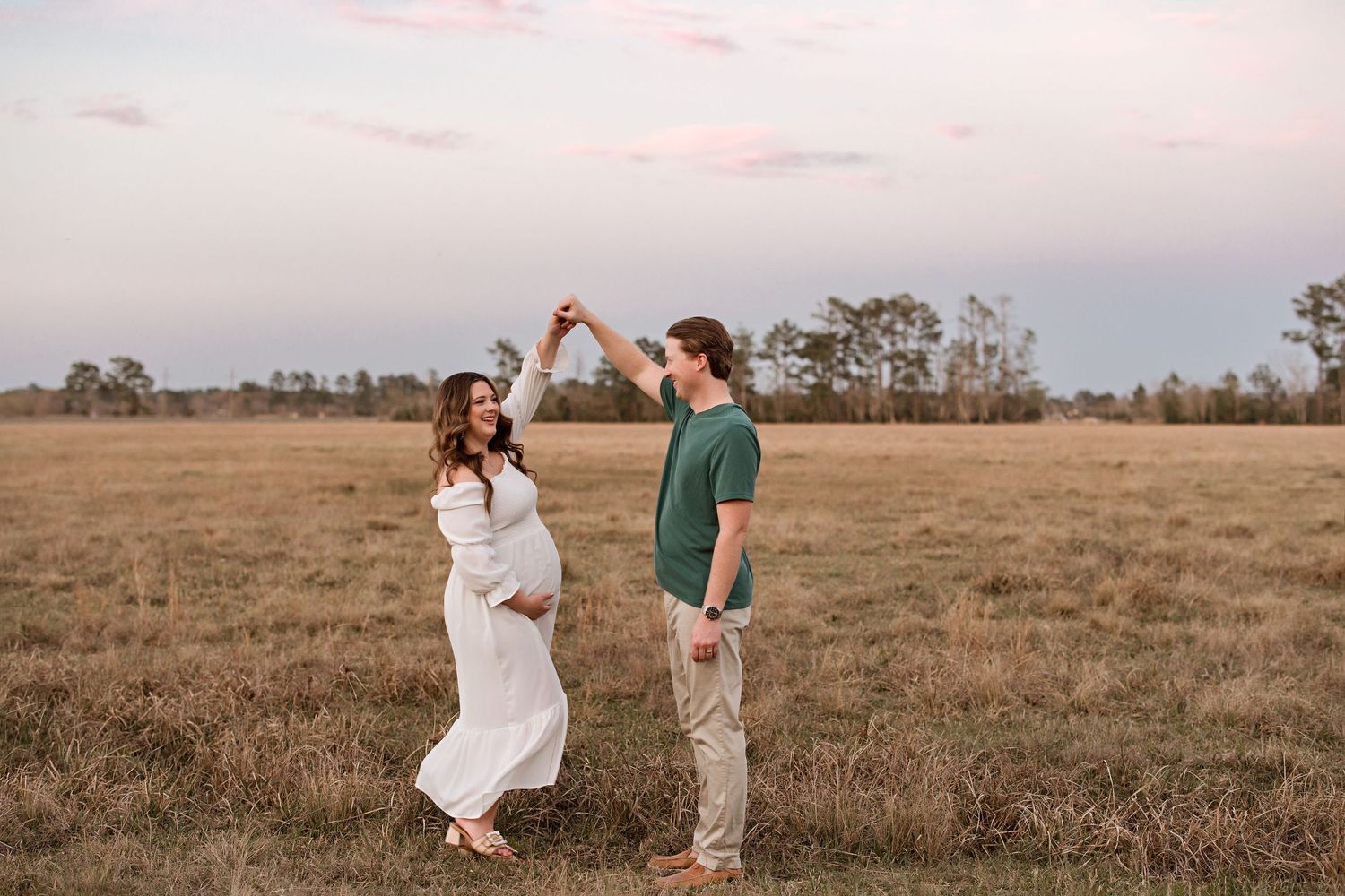 Couple dancing together at sunset in a rustic field with golden light with Bree Elle Photography in Bridge City, TX.