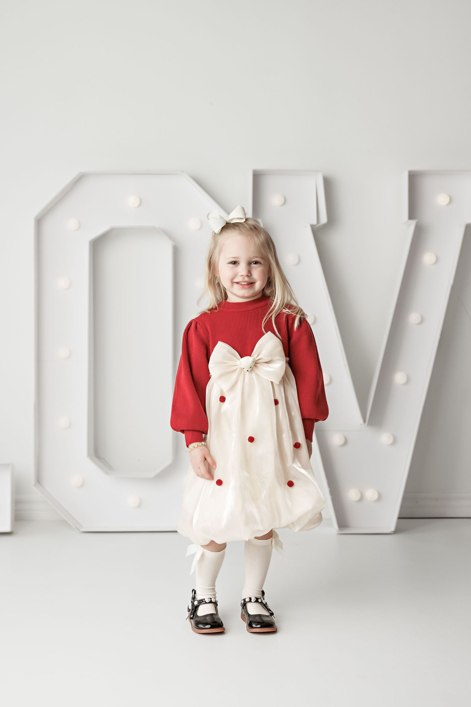 Portrait against large white LOVE letters with red and white holiday themed outfit.