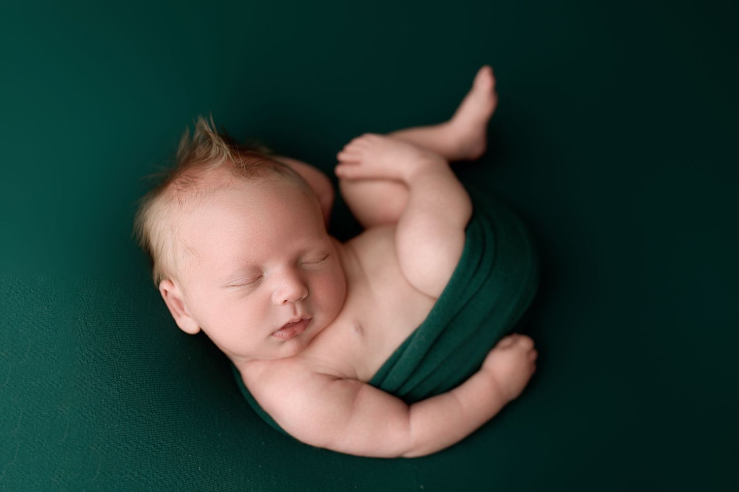 A collection of artistic newborn photography poses against a dark green background showing different angles and positions.