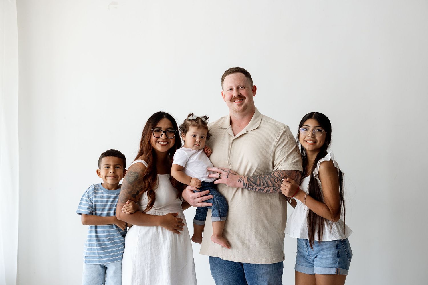 Happy family posing together against white wall at home for portrait session.