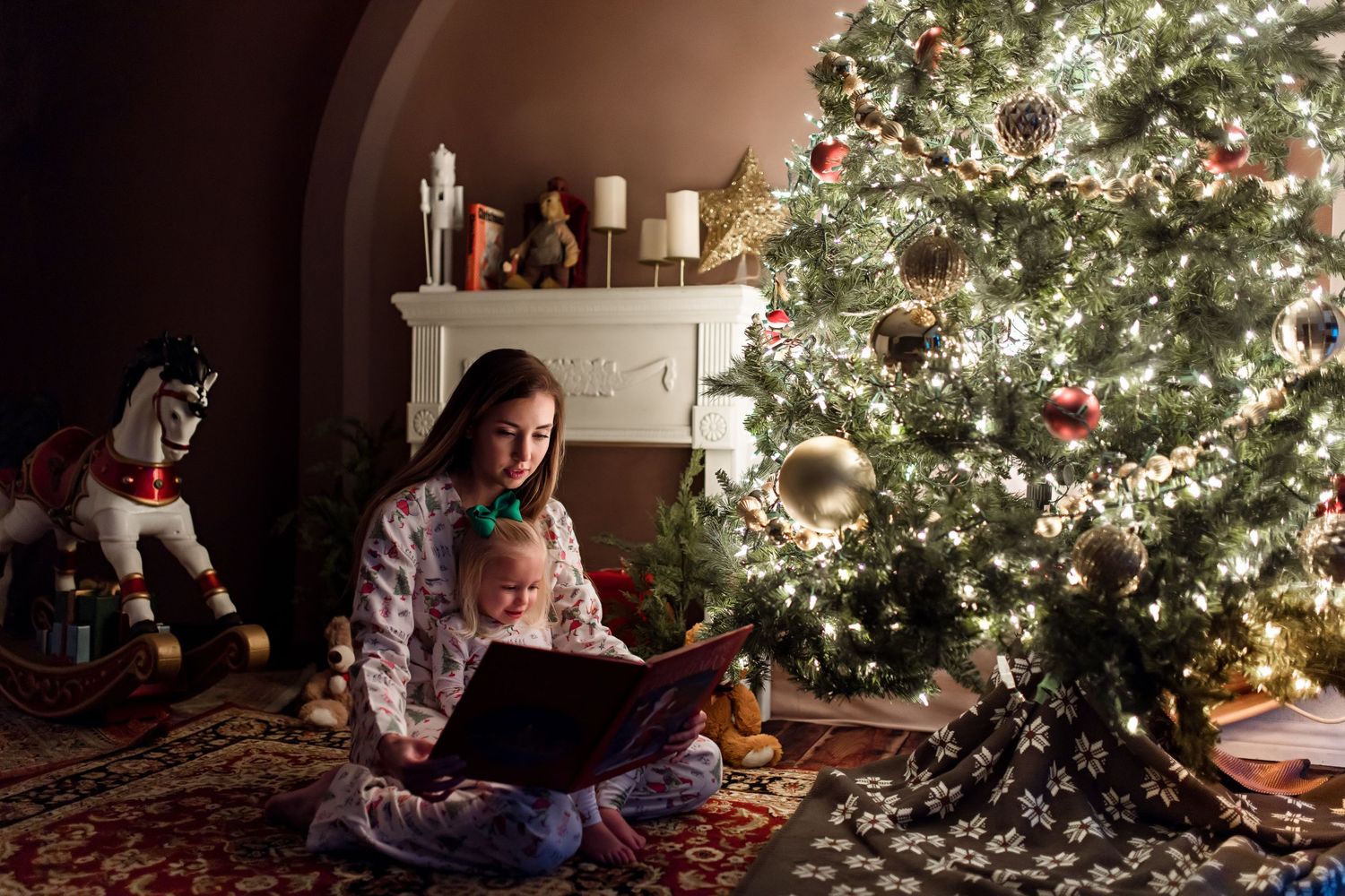A festively decorated living room features a glowing Christmas tree with twinkling lights and red ornaments.