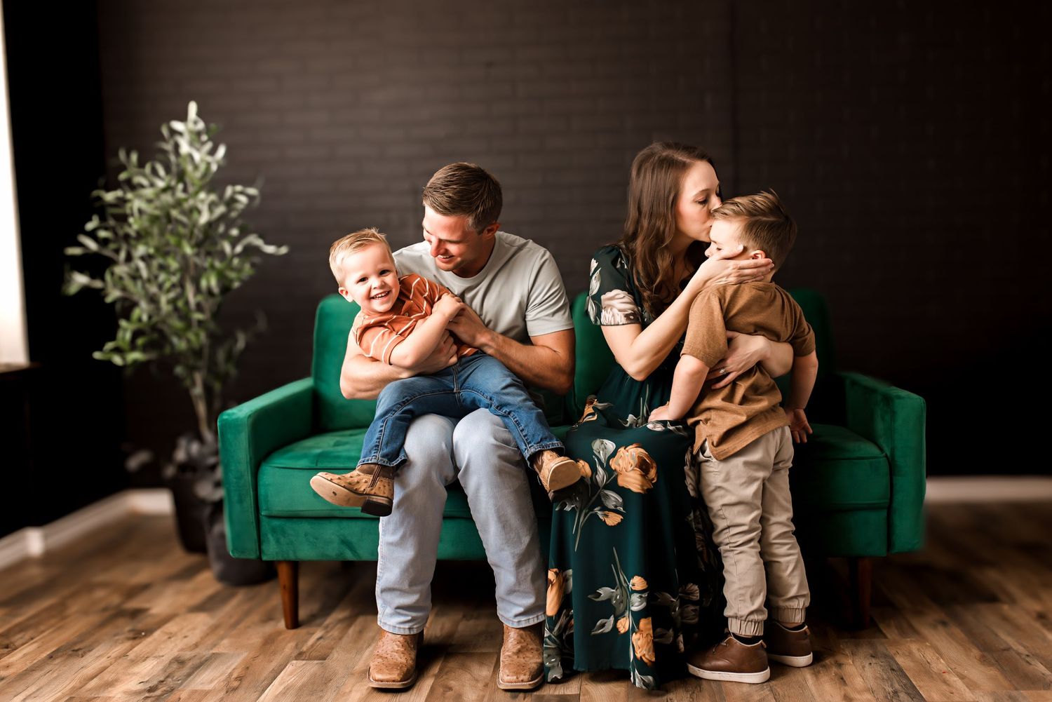 A cozy family moment together on a green velvet couch in a minimalist living room.
